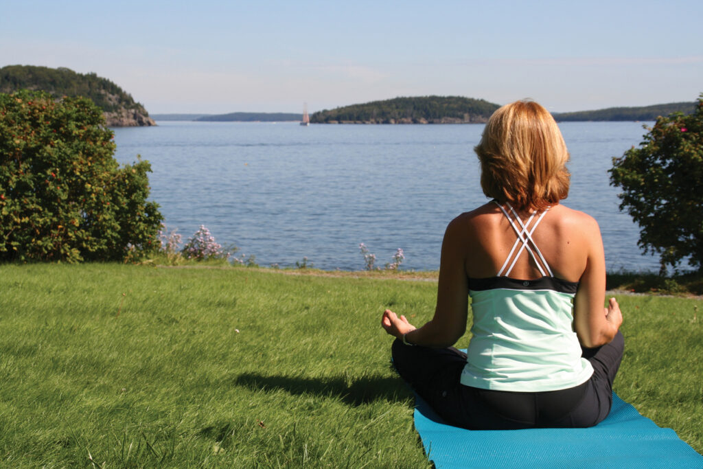Image of a woman in Yoga pose in front of the Bar Harbor Inn, Bar Harbor, Maine