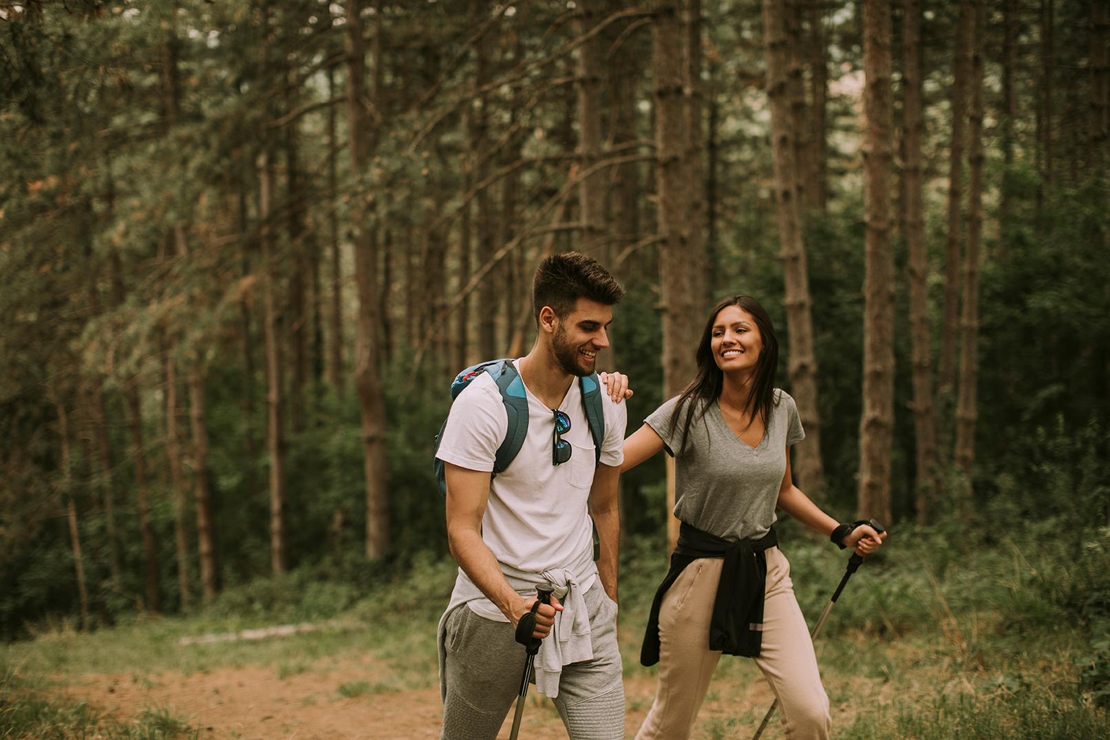 photo of Couple of young hikers with backpacks walk through the forest